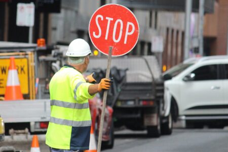 Older,Man,With,A,Stop,Sign,Directing,Traffic,In,Sydney